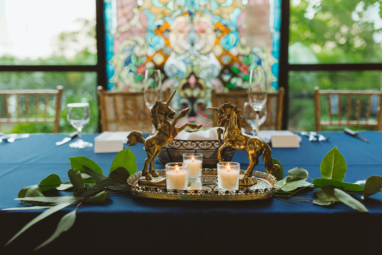 table centerpiece featuring unicorns and candles of gold and greenery at Grand Rapids Public Art Museum 