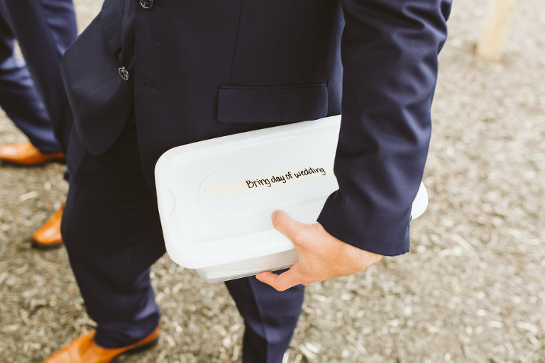 groom holding a box which says bring day of wedding