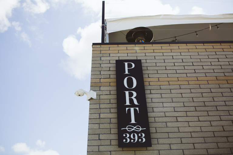 the sign outside of port 393 in holland michigan shows off the beautiful michigan blue skies and the set up on the roof for the outdoor party
