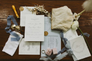 a flat lay of all the important wedding day paper details and rings including the brides vintage purse, grandmothers pen and small accessories