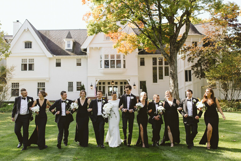 stunning wedding party in all black with only the bride in white in front of the Inn at Stonecliffe in Mackinac Island MI wedding venue
