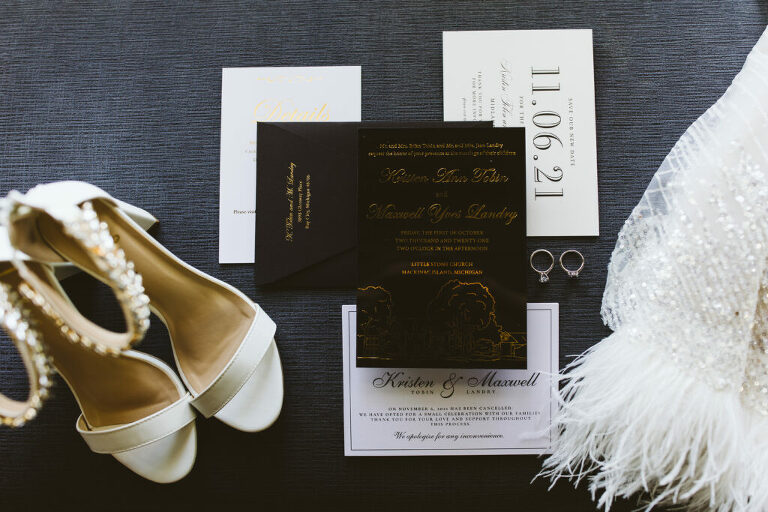 a photograph of the invitations, kristens shoes with sparkley ankles, the rings, and kristens sparkle dress with feathers 
